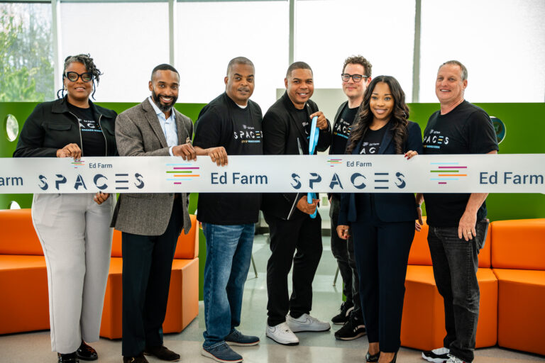 Seven people pose behind an Ed Farm SPACES ribbon at the InnoLab opening.