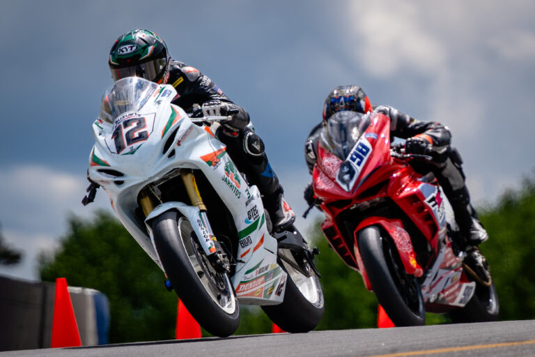 Two motorcycle racers lift their front wheels over a rise at Road Atlanta.