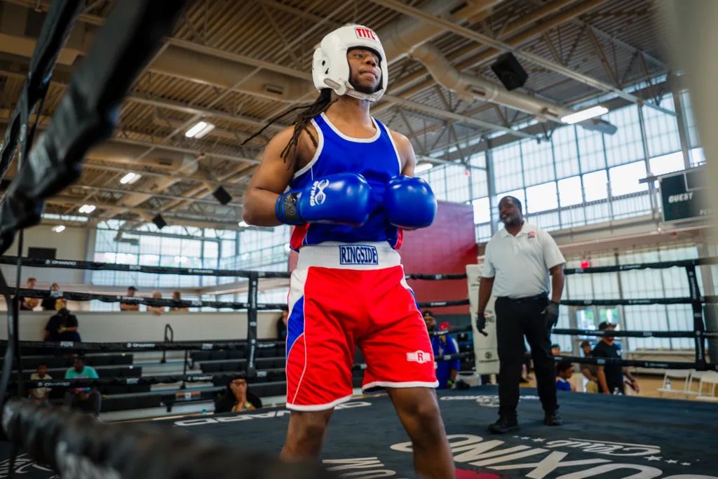 Amateur boxer in blue and red gear standing in a boxing ring