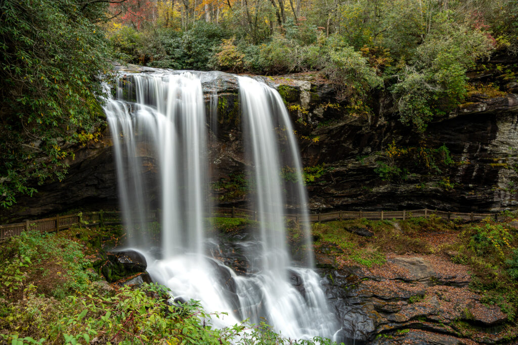 Long exposure of Dry Falls waterfall surrounded by autumn foliage in Highlands, North Carolina