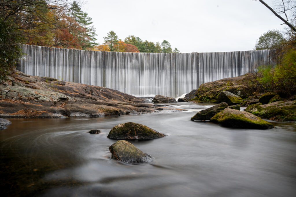 Long exposure of Sequoyah Falls waterfall flowing over a wide rock dam in late autumn
