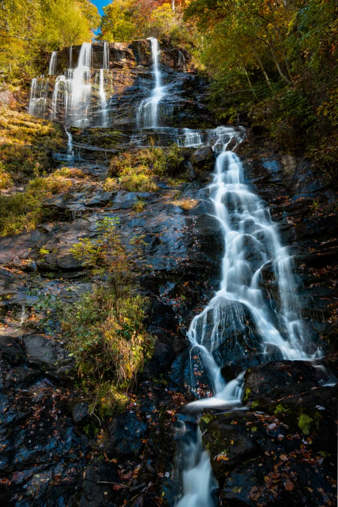 Tall Amicalola Falls waterfall cascading over dark rock in autumn forest