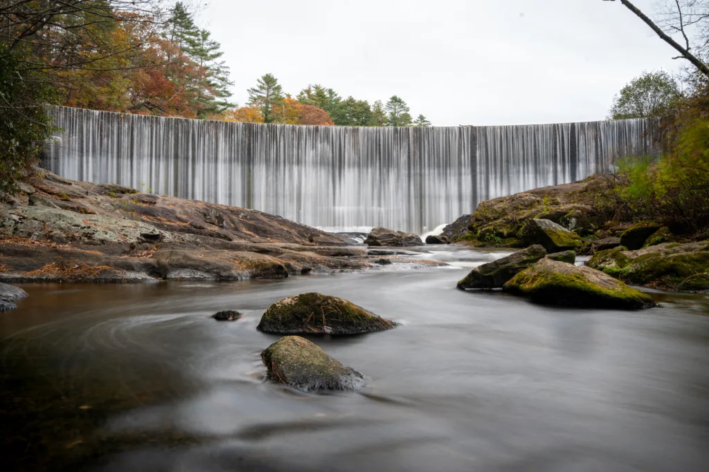 Long exposure of Sequoyah Falls waterfall flowing over a wide rock dam in late autumn