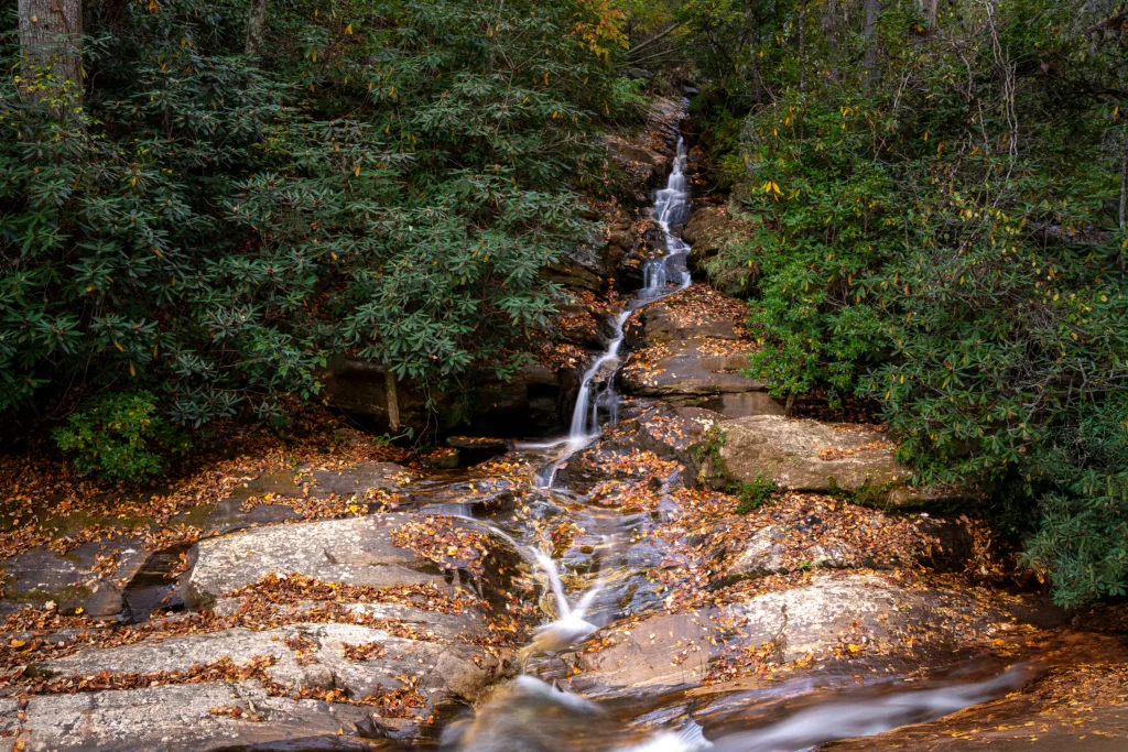 Narrow Dukes Creek Falls stream flowing over rocks amid fall foliage