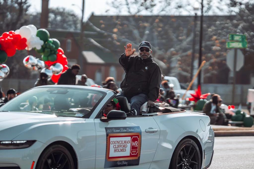 Councilman waves from white convertible in festive holiday parade