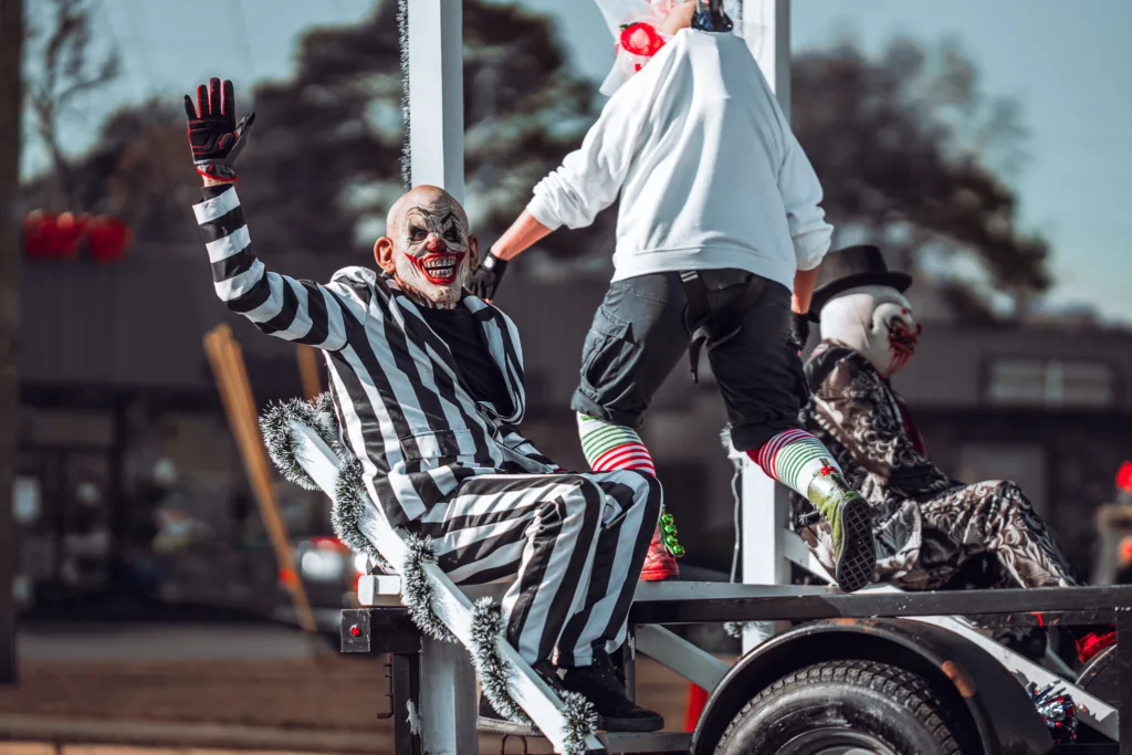 Clown in black and white stripes waving from a parade float