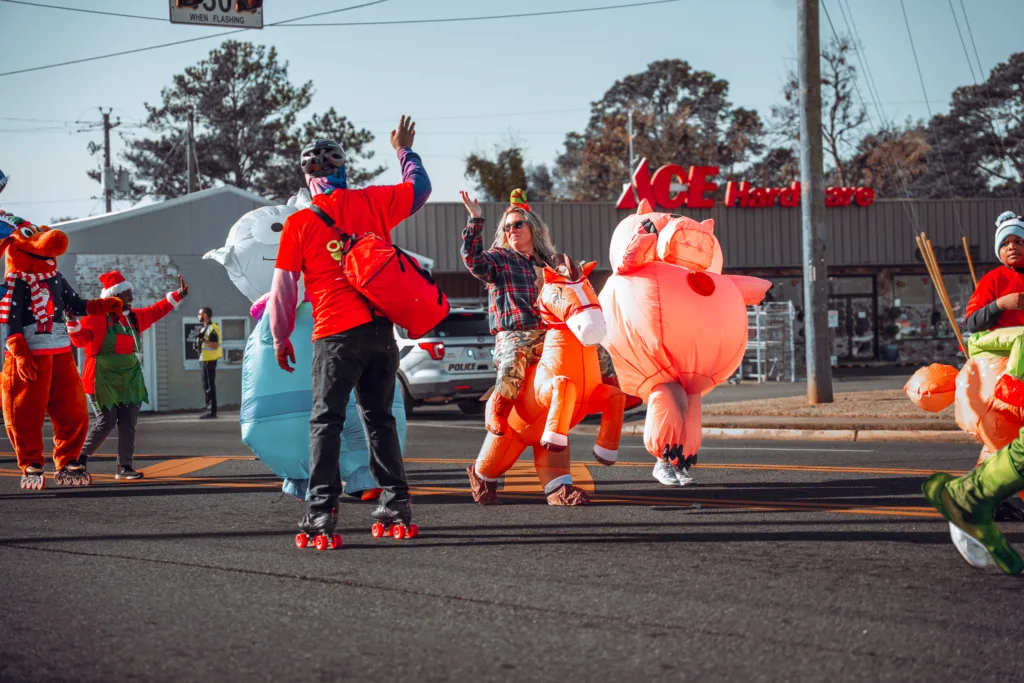 People in bright inflatable costumes skating and walking in a holiday parade