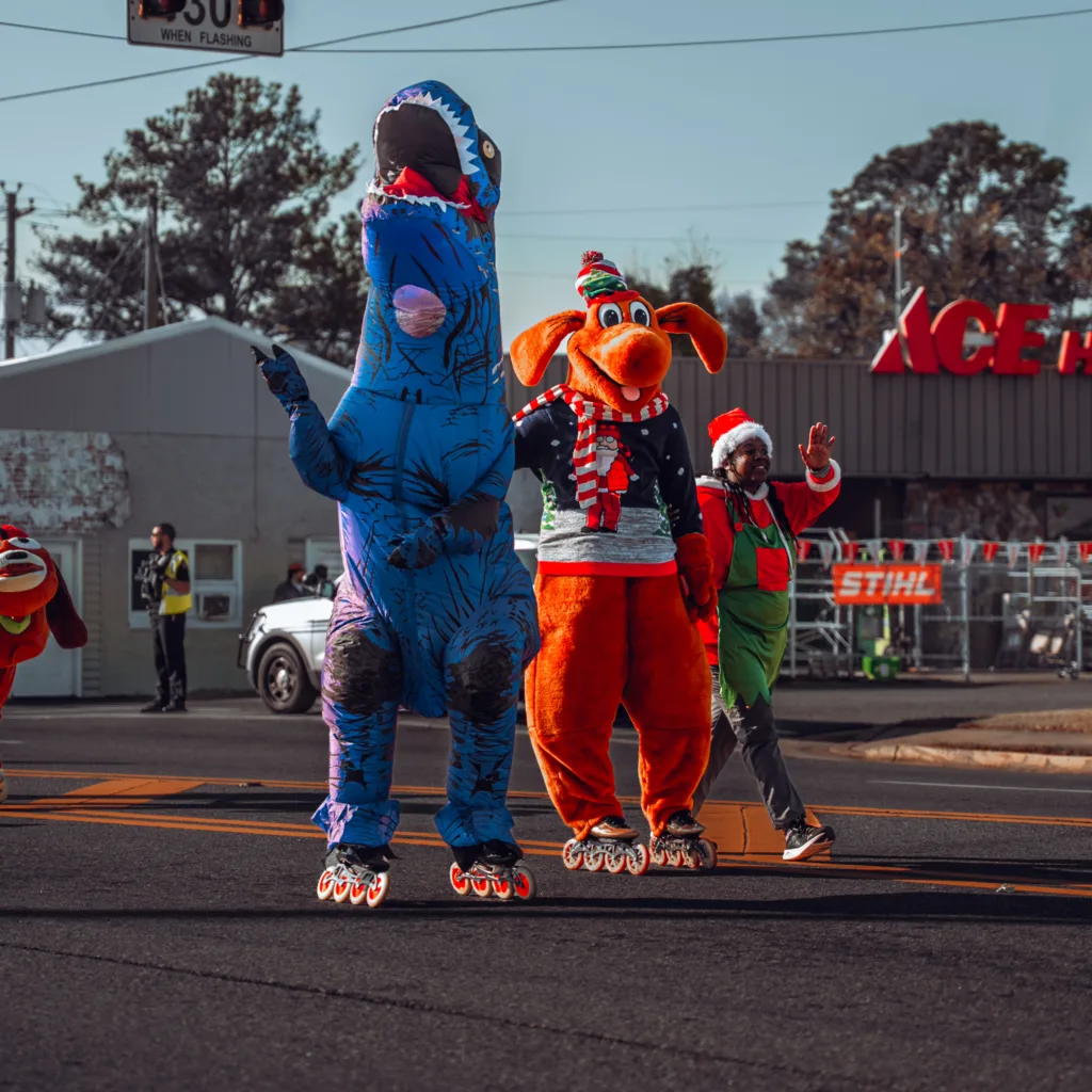 People in dinosaur and dragon costumes walking in a festive street parade