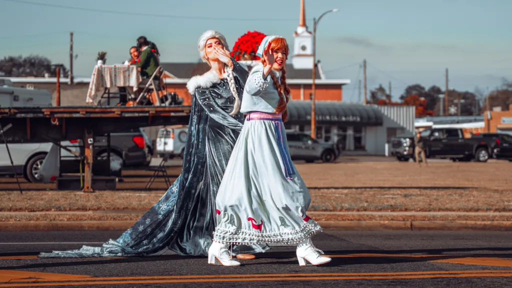 Two costumed performers in winter dresses walking in a street parade