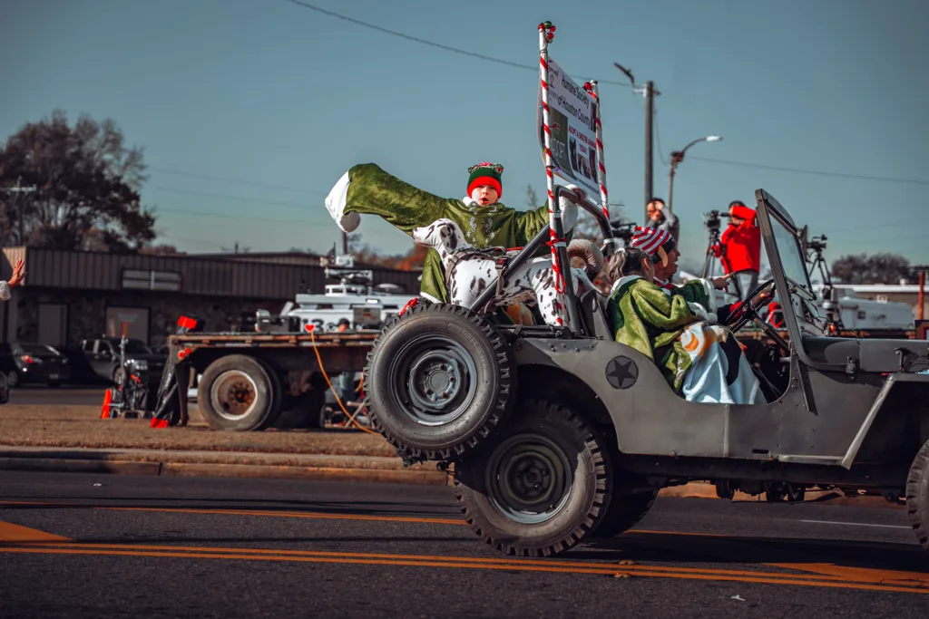 Children bundled in blankets ride in a decorated jeep during a holiday parade