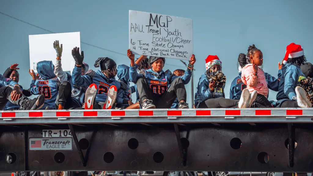 Youth football players in jerseys riding on a flatbed parade float