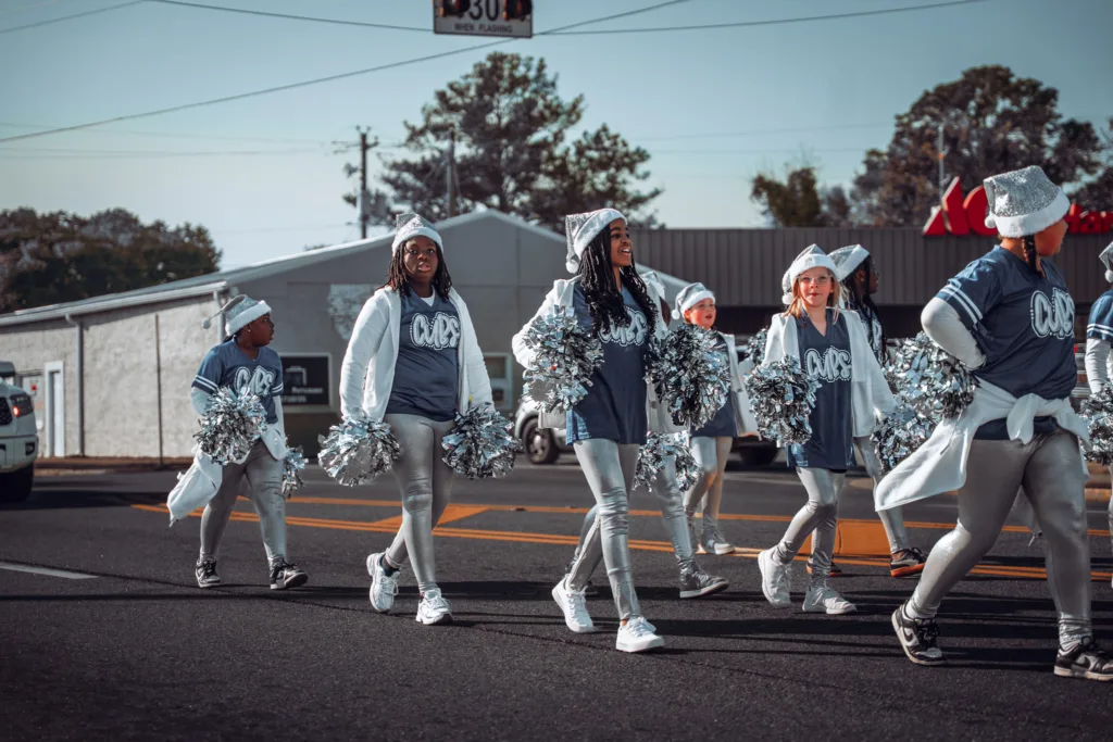 Youth cheer squad in matching outfits marching with pom-poms in a street parade