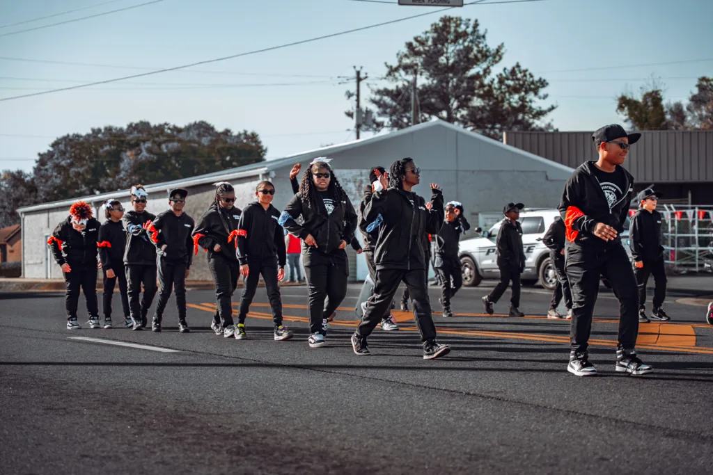 Group of people in matching black outfits walking in a street parade