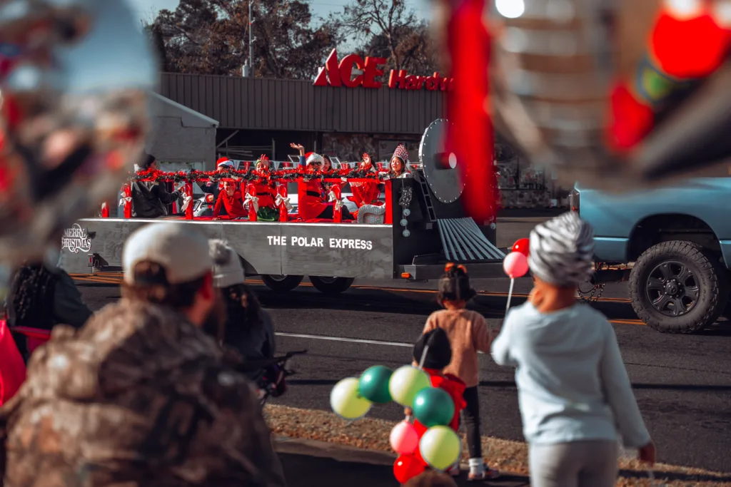 Children on The Polar Express Christmas parade float passing spectators with balloons