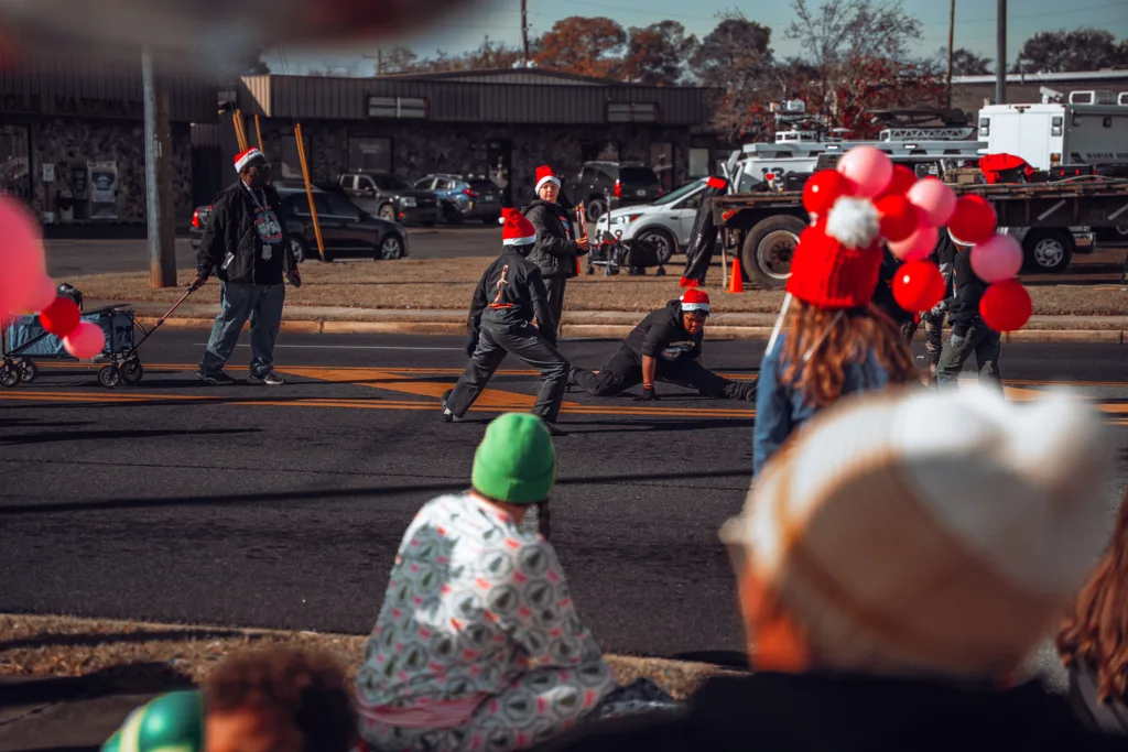 Children watch performers in Santa hats during a holiday street parade