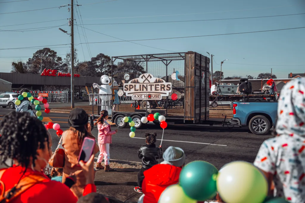 Children watching a Splinters Axe House parade float with balloons