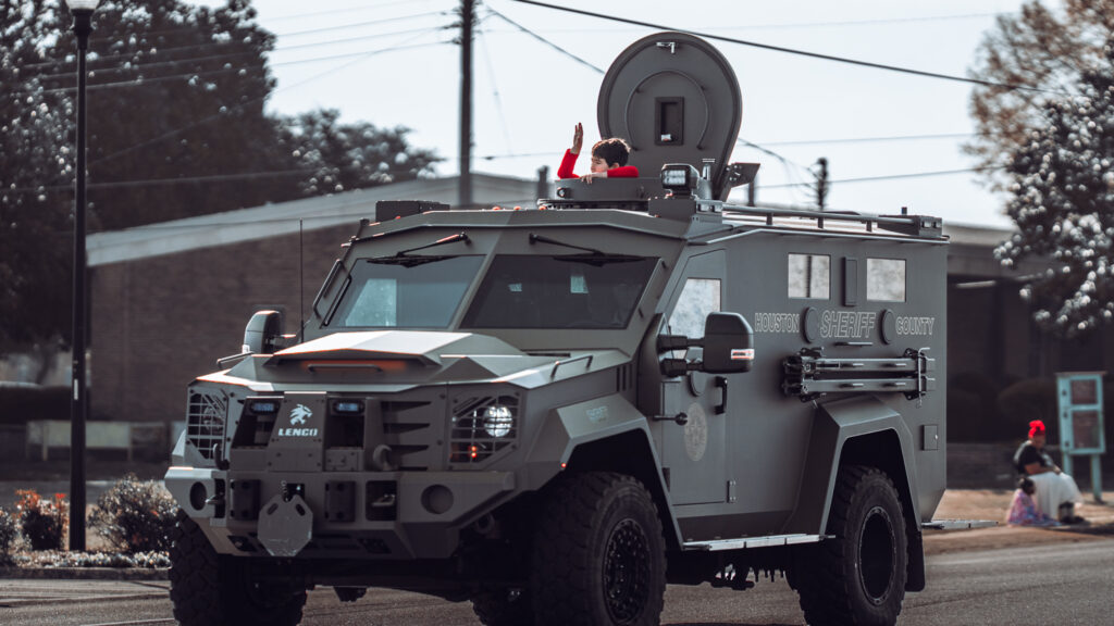 Armored police vehicle with turret driving down a city street