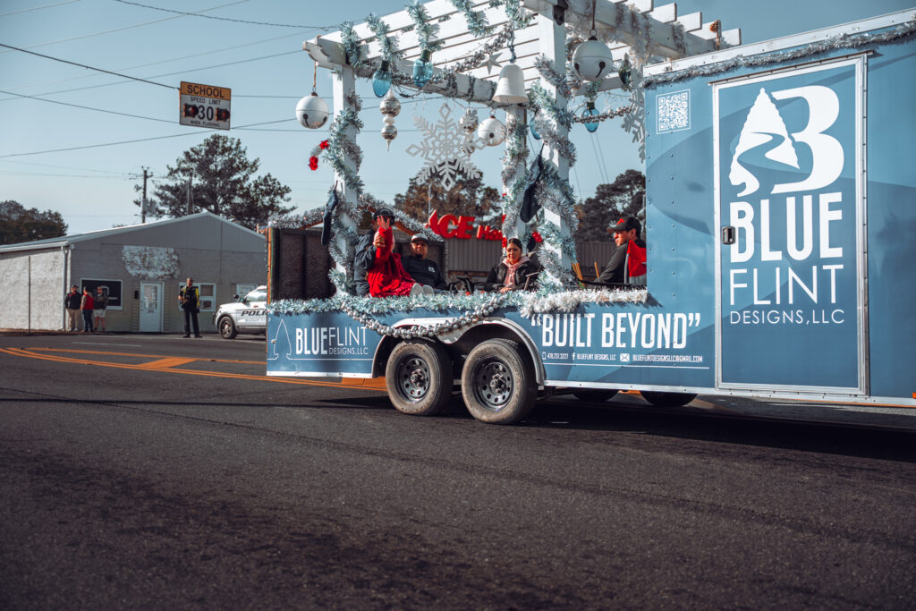 Blue Flint Designs decorated trailer float driving in a holiday parade