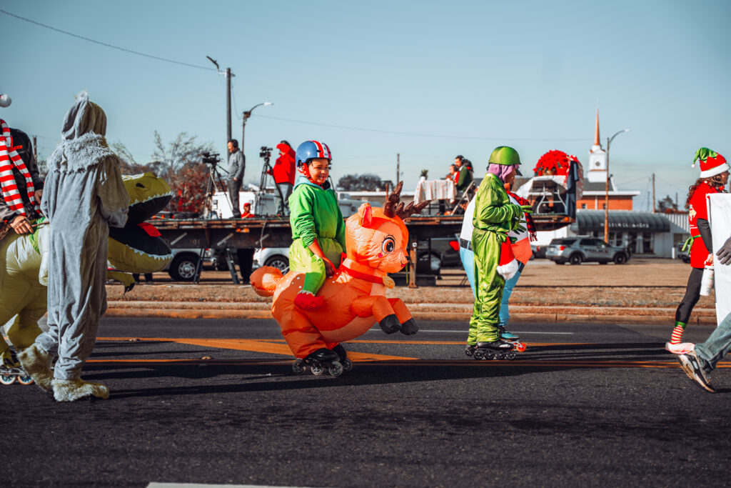 Children in bright costumes walking and riding inflatable animals in a street parade