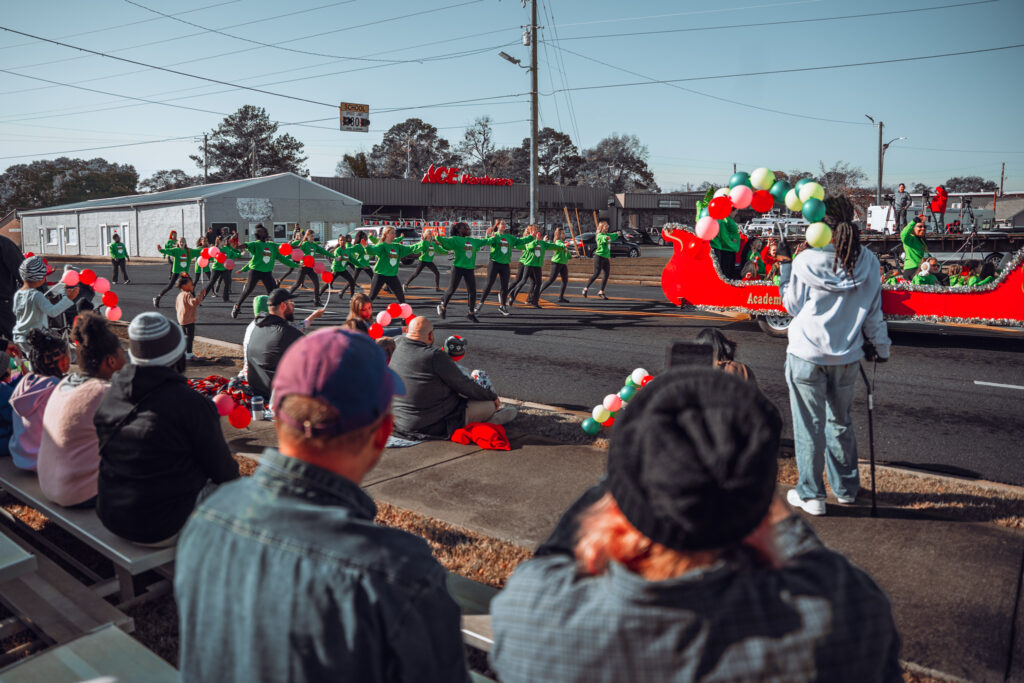 Spectators watch a festive red holiday parade float with dancers