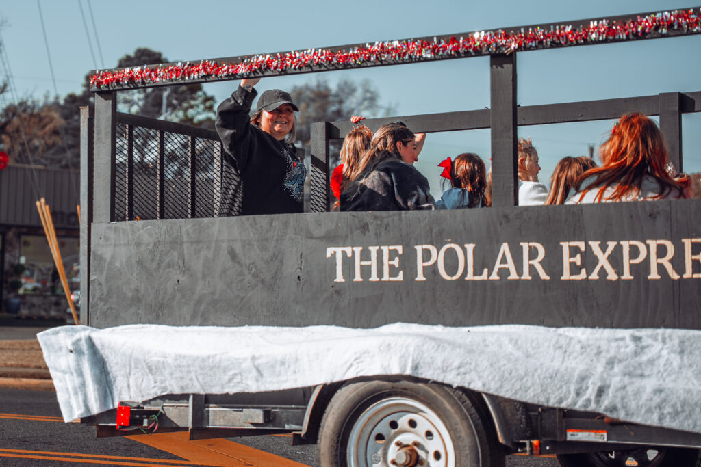Parade float decorated as The Polar Express with smiling riders waving