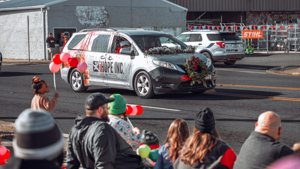 Decorated Hope Inc. van drives in a holiday parade past spectators