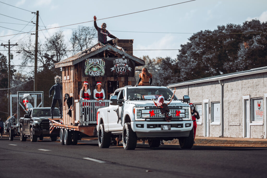 White pickup truck pulling festive parade float with people waving