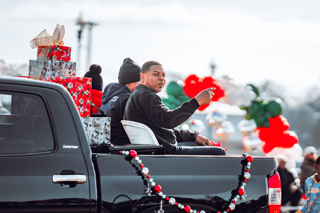 People riding in pickup truck decorated with gifts and holiday garlands