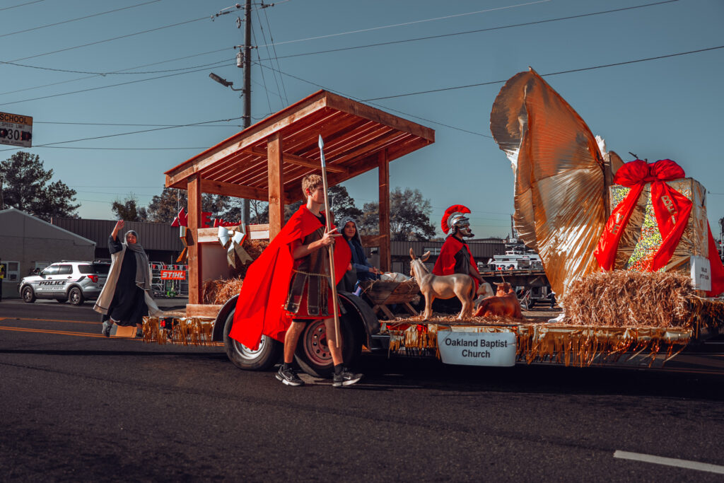 Oakland Baptist Church Christmas parade float with costumed participants and hay bales