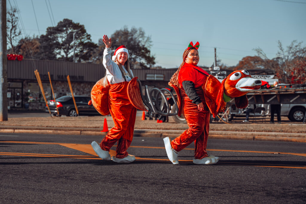 Two people in bright orange animal costumes walking in a street parade