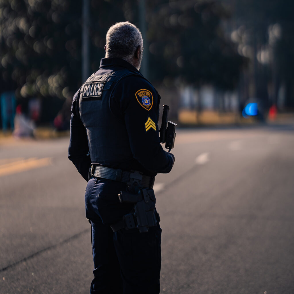 Police officer standing on a quiet street holding a radio