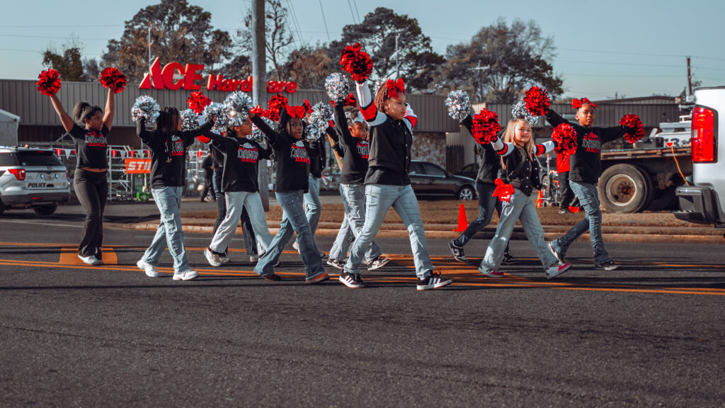 Youth cheer squad walking in formation with red and silver pom poms