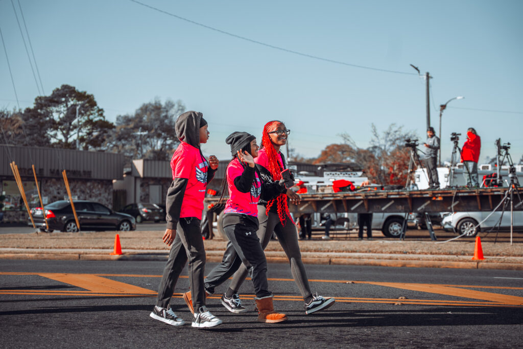 Three young people in bright shirts walking together in a street parade