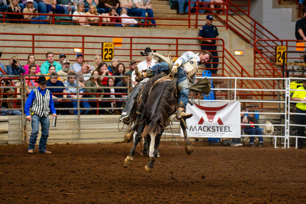 Cowboy in bareback bronc riding event at indoor rodeo