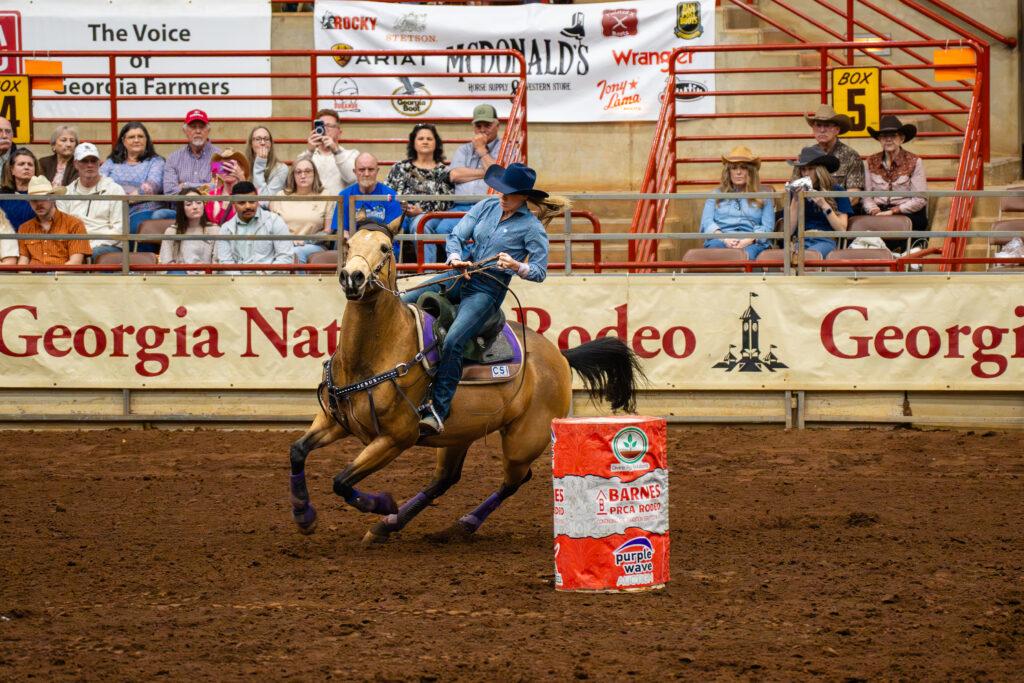 Cowgirl on galloping horse rounding a barrel at Georgia National Rodeo