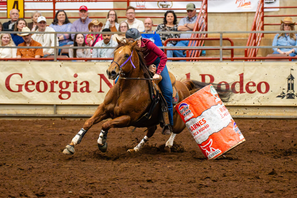 Barrel racer on galloping horse rounding a barrel at Georgia National Rodeo