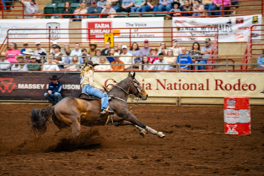 Cowgirl barrel racing on a galloping horse at Georgia National Rodeo