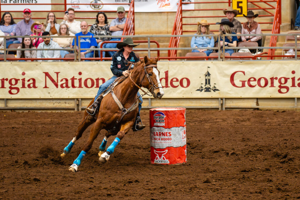 Cowgirl on horse rounding a barrel in an indoor rodeo arena