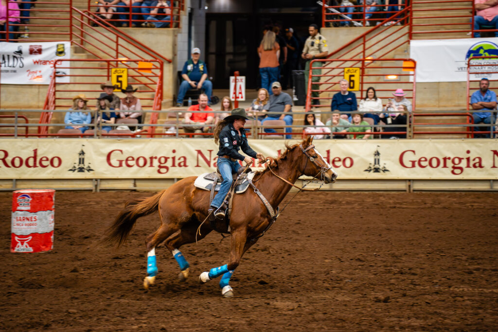 Cowgirl on galloping horse rounding a barrel at Georgia National Rodeo