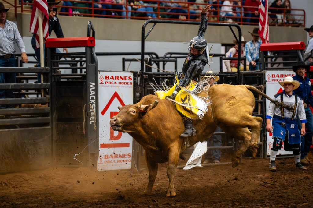 Bull rider in protective gear hanging on during a powerful rodeo ride