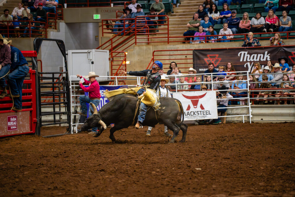 Bull rider holding on during a ride in an indoor rodeo arena