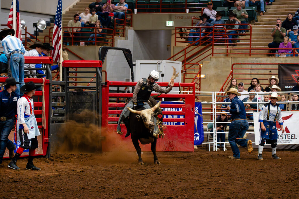 Bull rider holding on with one arm raised during rodeo event