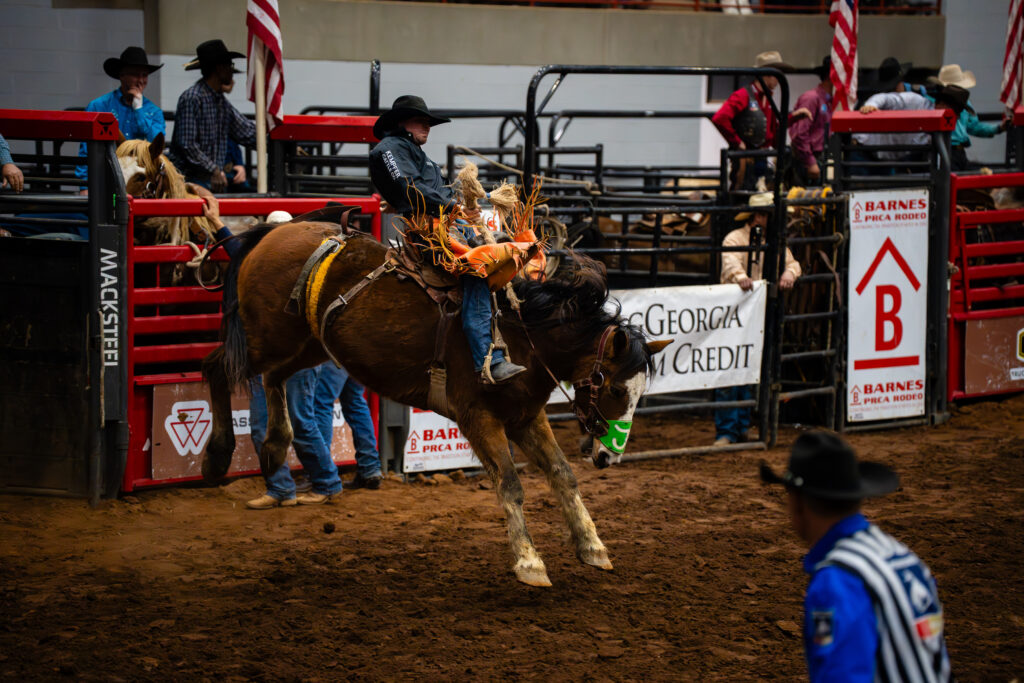 Cowboy riding a bucking horse in a saddle bronc event at a rodeo